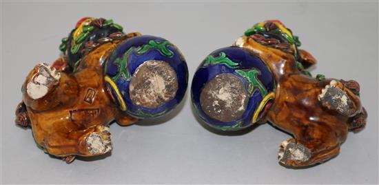 A pair of Chinese polychrome pottery figures of lion-dogs with balls, height 12cm